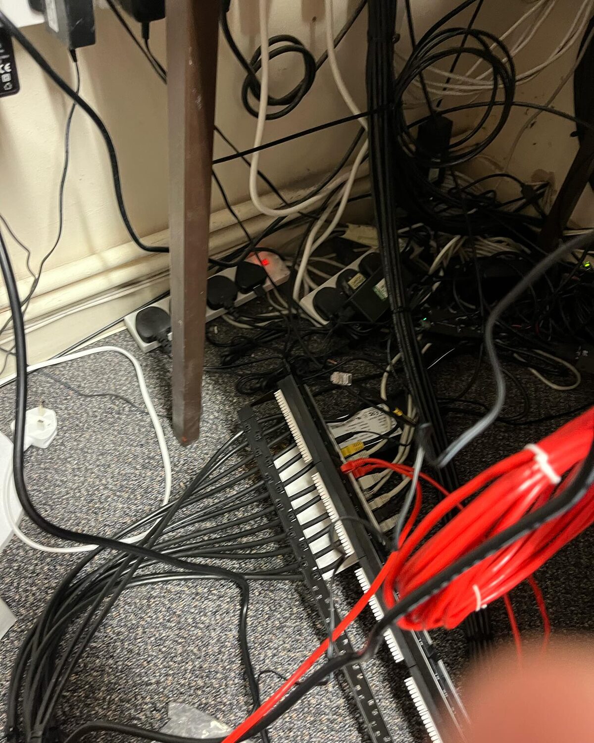 Tangled mess of old cables, power strips and adapters on the floor before the new network install